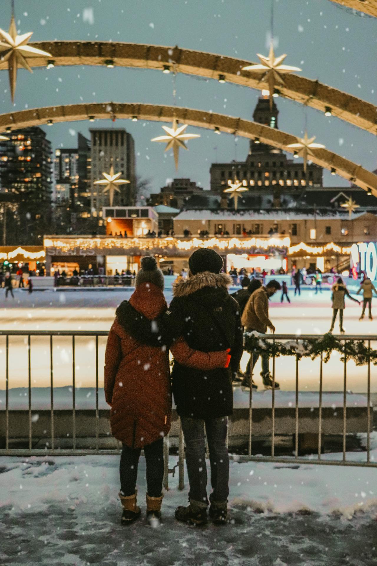 Prepárate: ¿Viajas en Navidad? Así es el clima de Canadá en diciembre en Travel & Life: Tu Guía de Viajes y Estilo de Vida Pareja disfrutando de una Navidad en Toronto, frente a una pista de hielo. Refleja el clima de Canadá en Diciembre