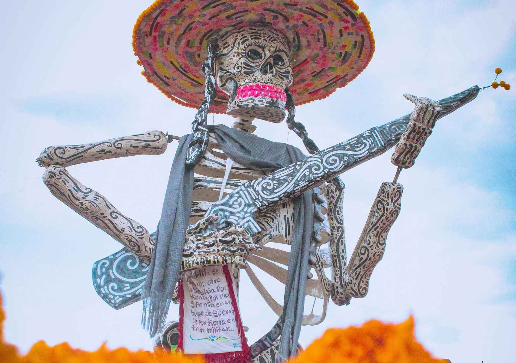 Escultura de Calavera de Día de Muertos, con flores de cempasúchil y el cielo de fondo en Atlixco