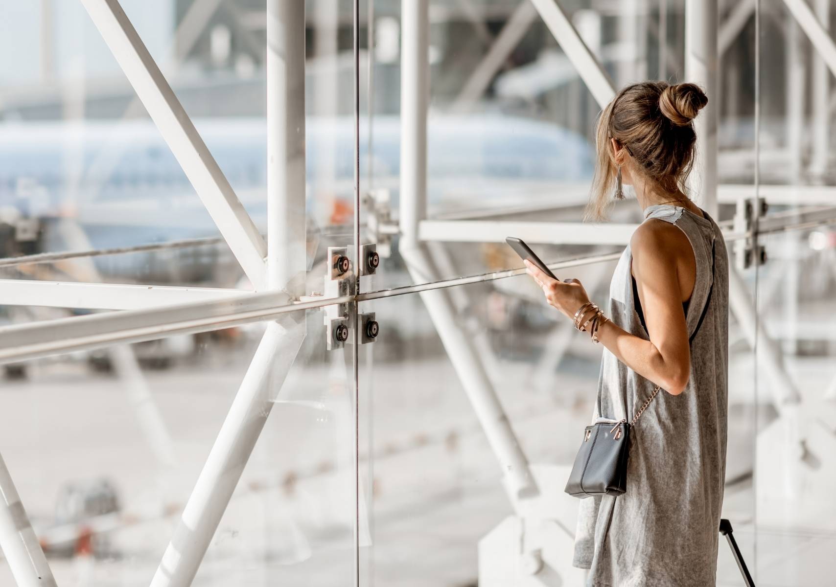 Mujer viendo un avión por el ventanal del aeropuerto. Compró sus boletos en el Buen Fin 2025