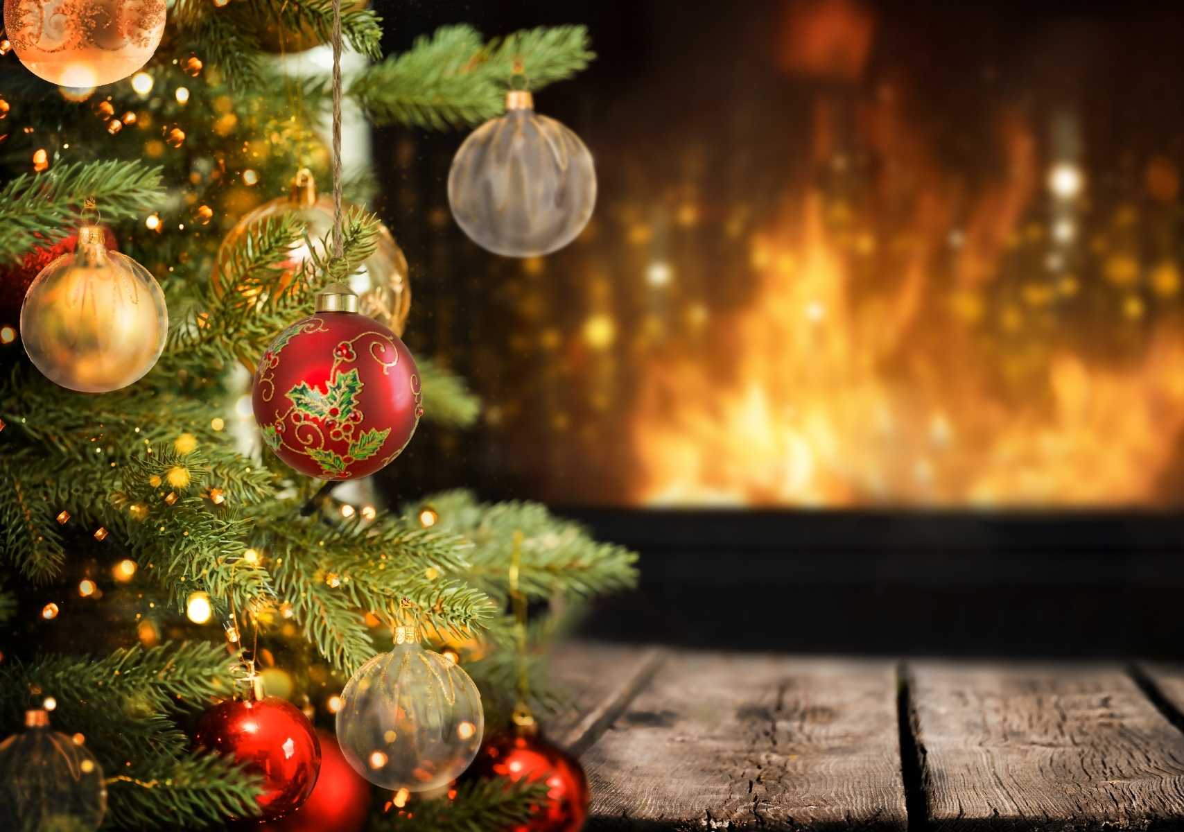 árbol de Navidad natural con esferas rojas y transparentes, de fondo una chimenena