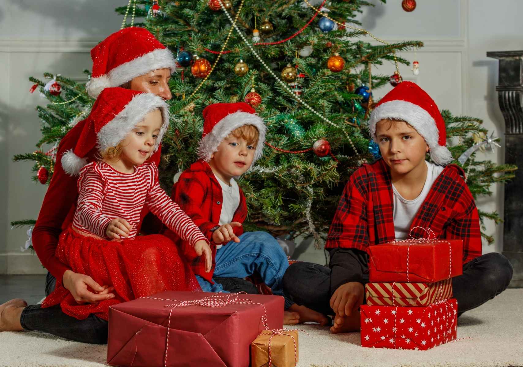 niños disfrutando de sus regalos frente al árbol de Navidad en un día sin clases