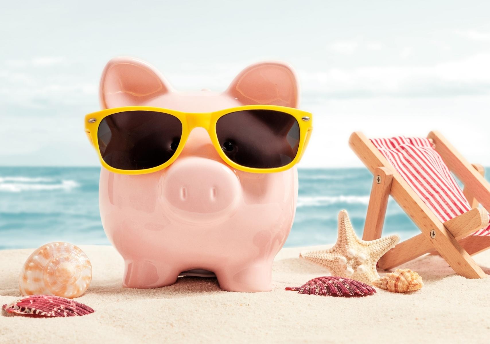 Una alcancía de cochinito en la playa para ilustrar los métodos de ahorro para poder viajar